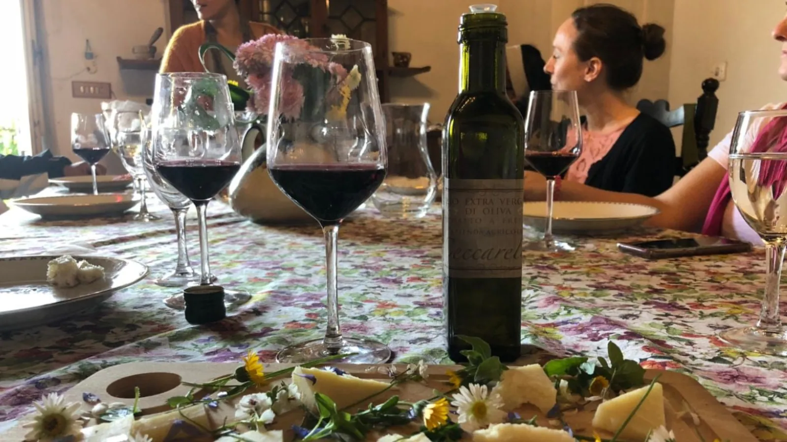 Table with red and white wine, cheese and flowers on a floral tablecloth