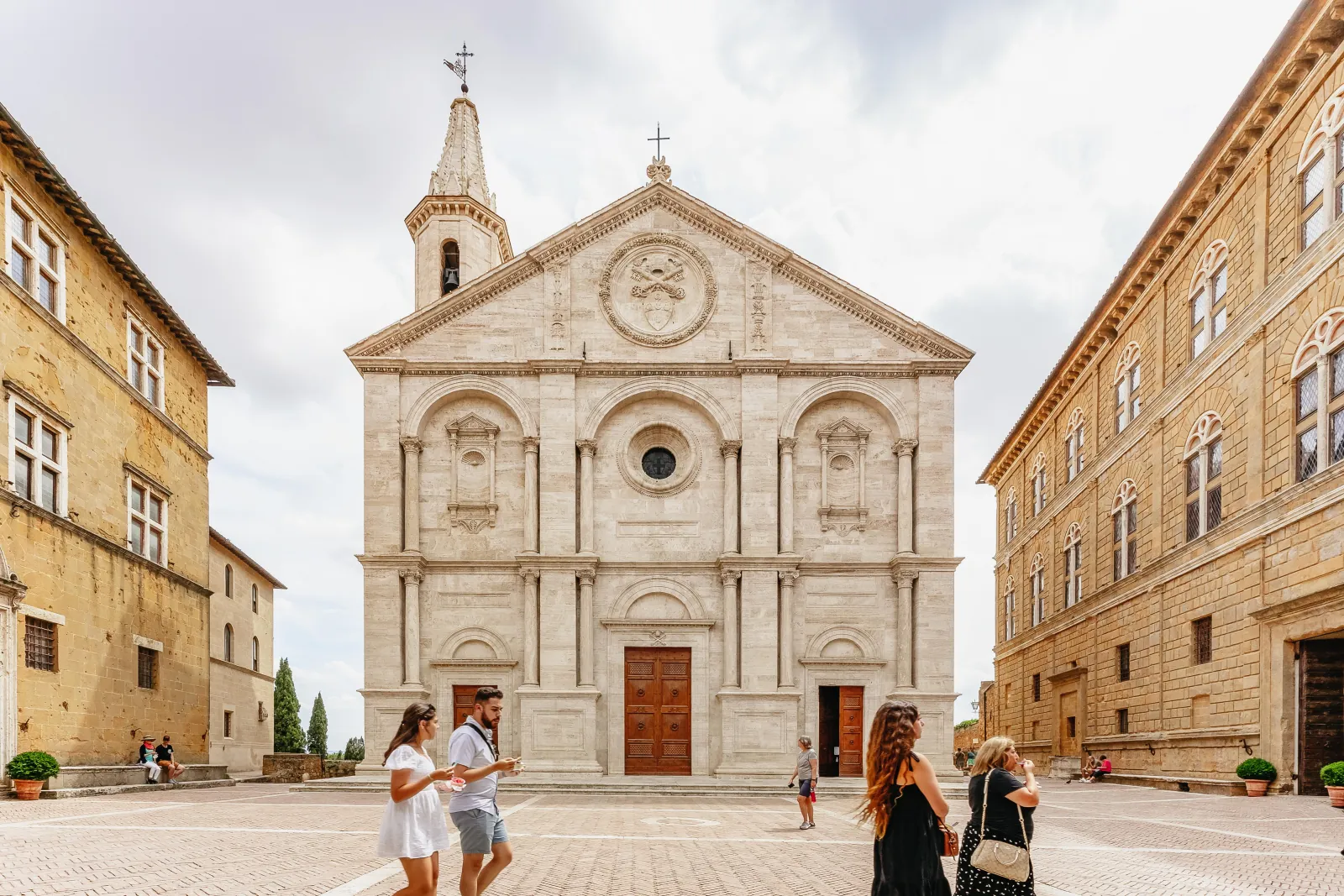 Pale stone cathedral facade on a quiet square in Pienza with palaces on both sides