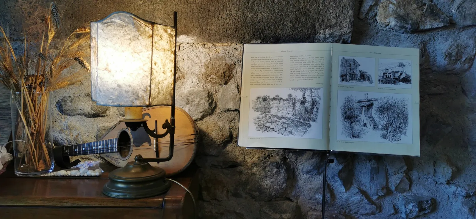 Mandolin, lamp and open book of sketches against a rough stone wall