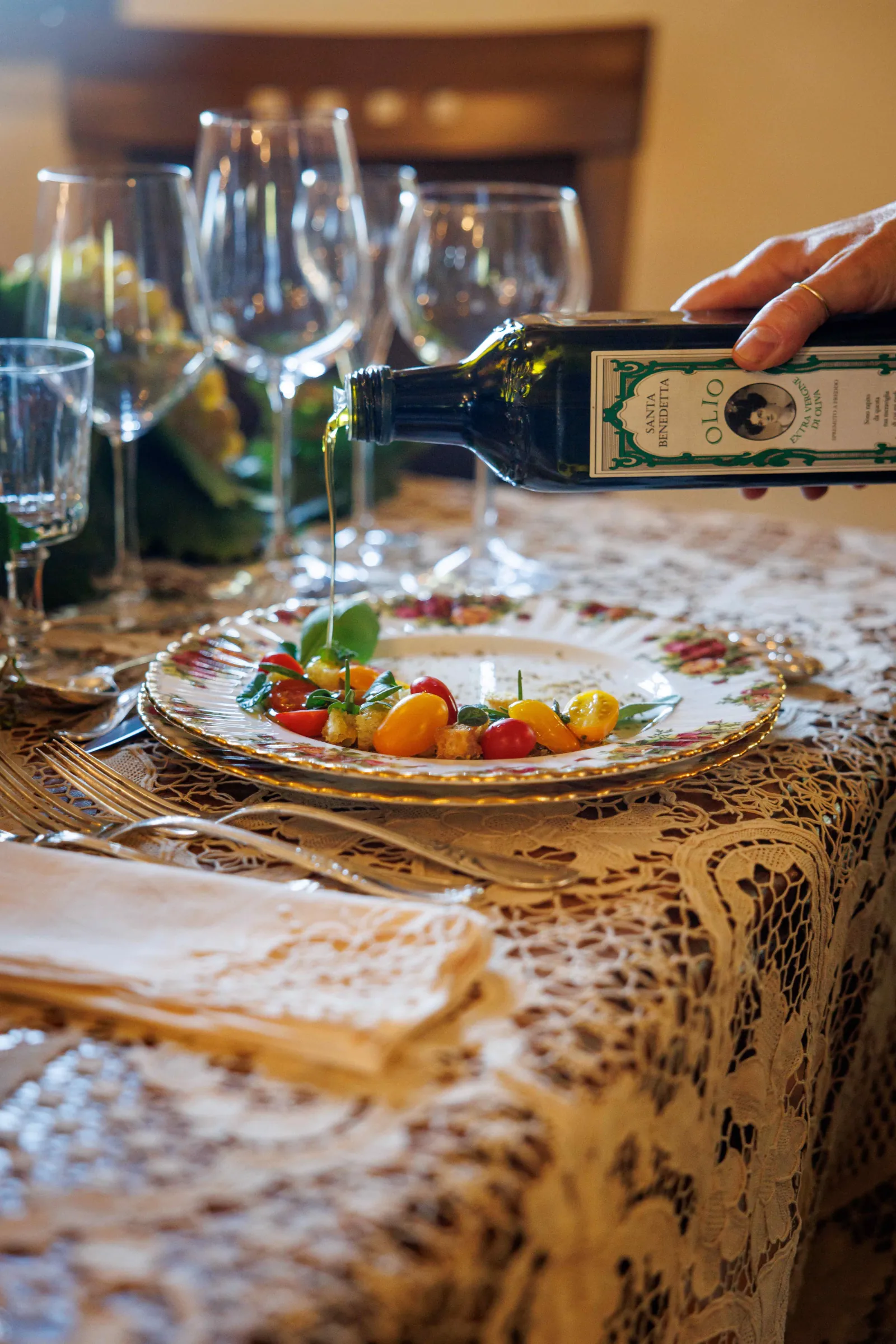 Olive oil being poured over a colourful tomato starter on a floral plate