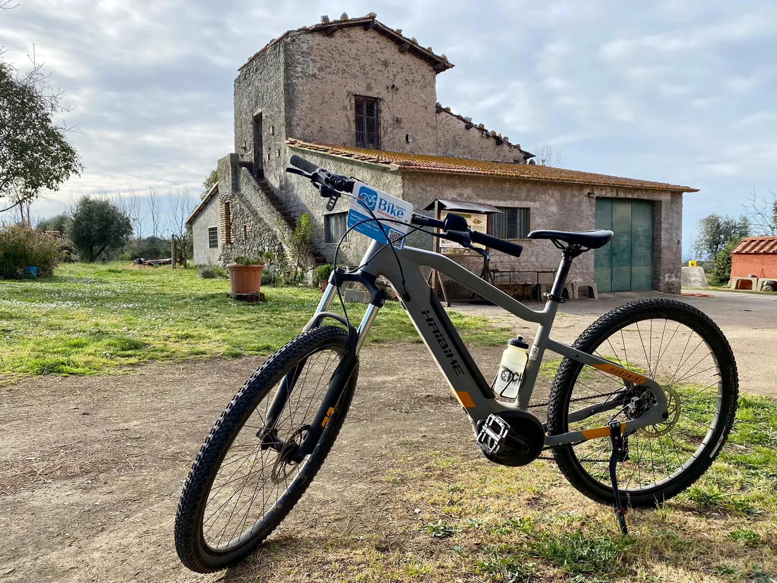E-bike parked on a dirt yard in front of an old stone farm building