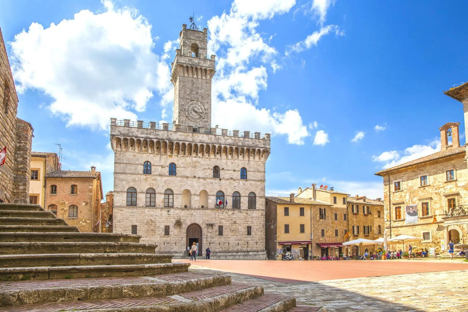 Crenellated town hall and stone steps on a sunny Montepulciano square