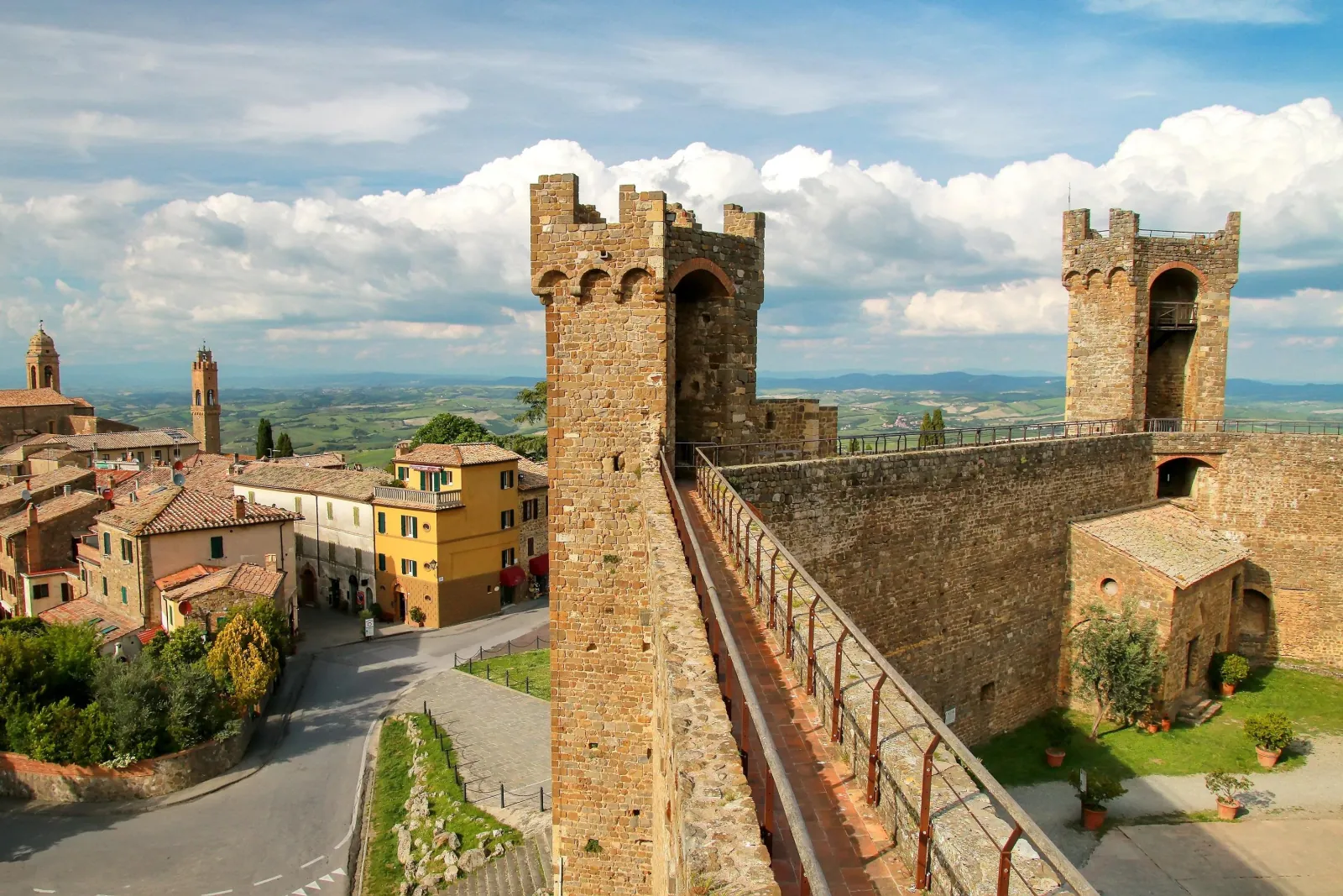 Stone towers and ramparts of the Montalcino fortress above terracotta rooftops and countryside