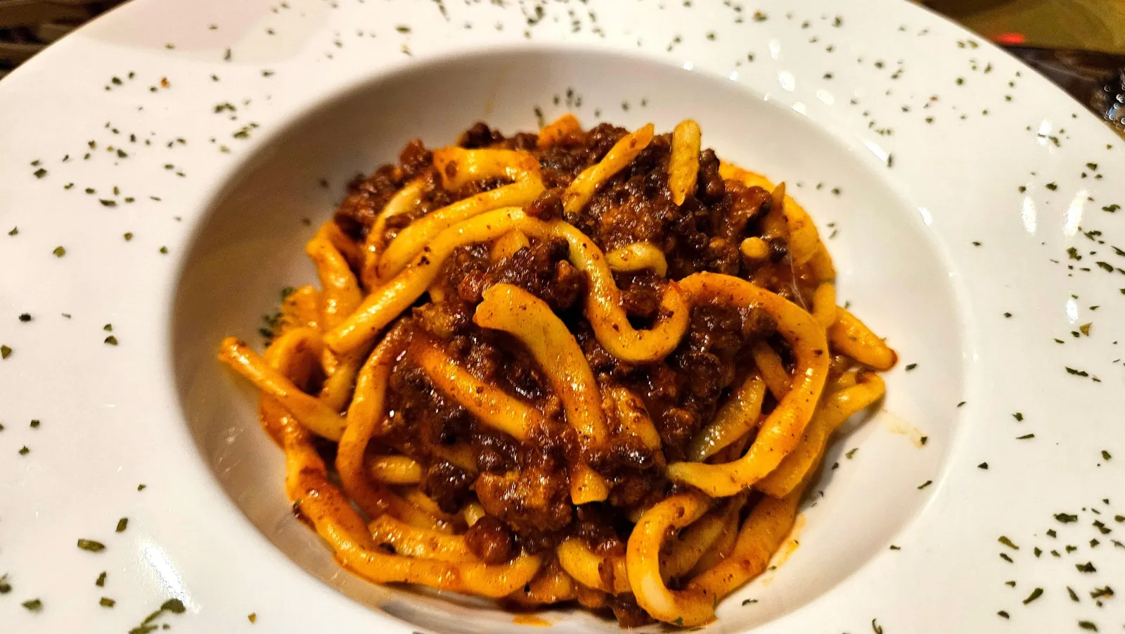 White bowl of hand-cut pasta with meat ragu, close up
